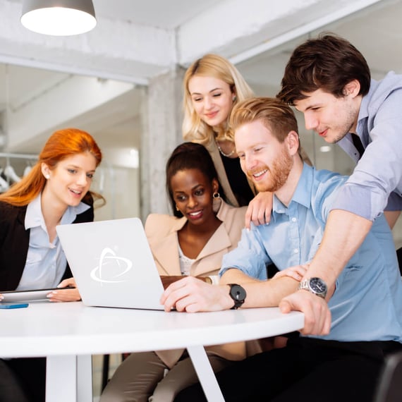 Five young professionals gathered around a laptop, smiling and collaborating in a modern office setting | brand awreness SUNZINET